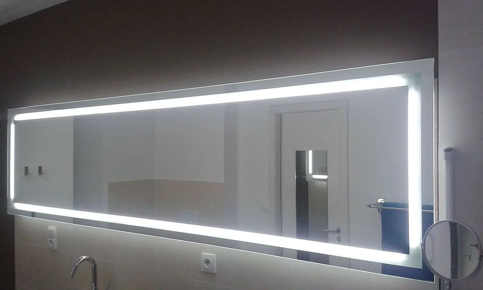 Grand miroir rectangulaire rétroéclairé par un cadre de LED, au-dessus d'un lavabo