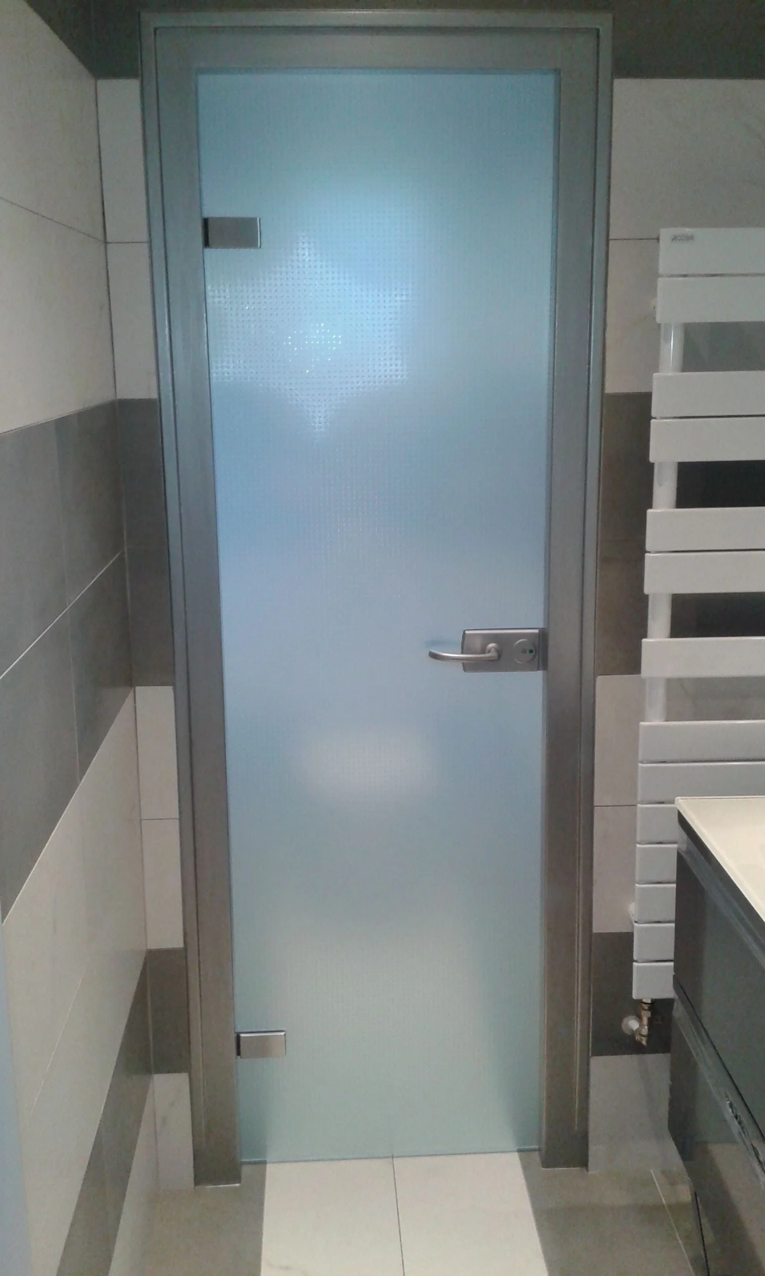 Porte de salle de bains en verre dépoli à motif, dans un huisserie aluminium